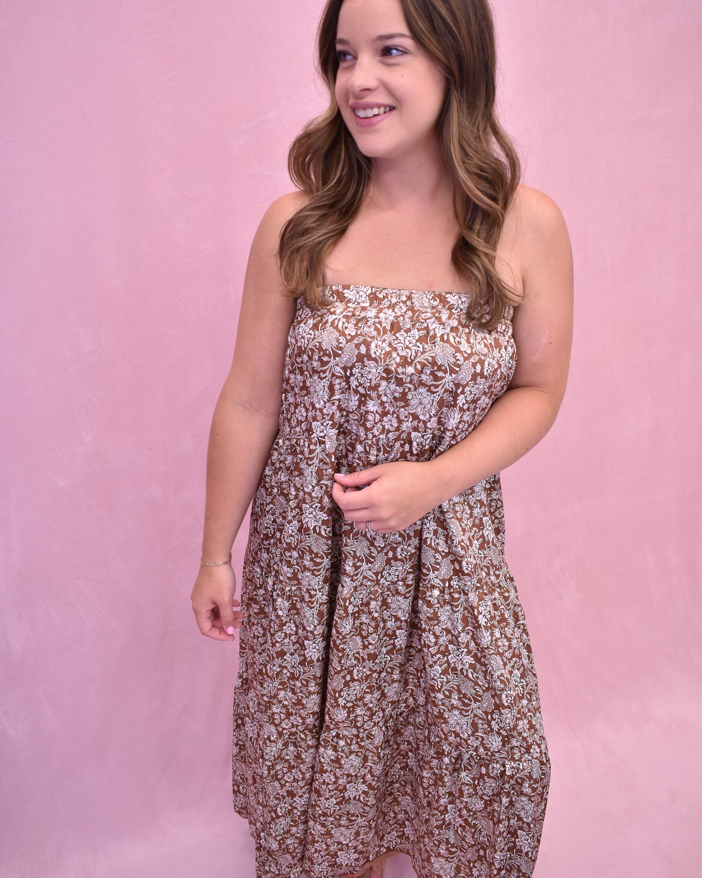 Woman wearing a floral strapless dress against a pink background