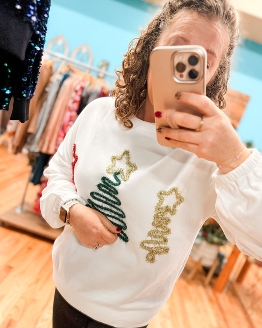 Person wearing a white sweater with Christmas-themed designs in a store setting