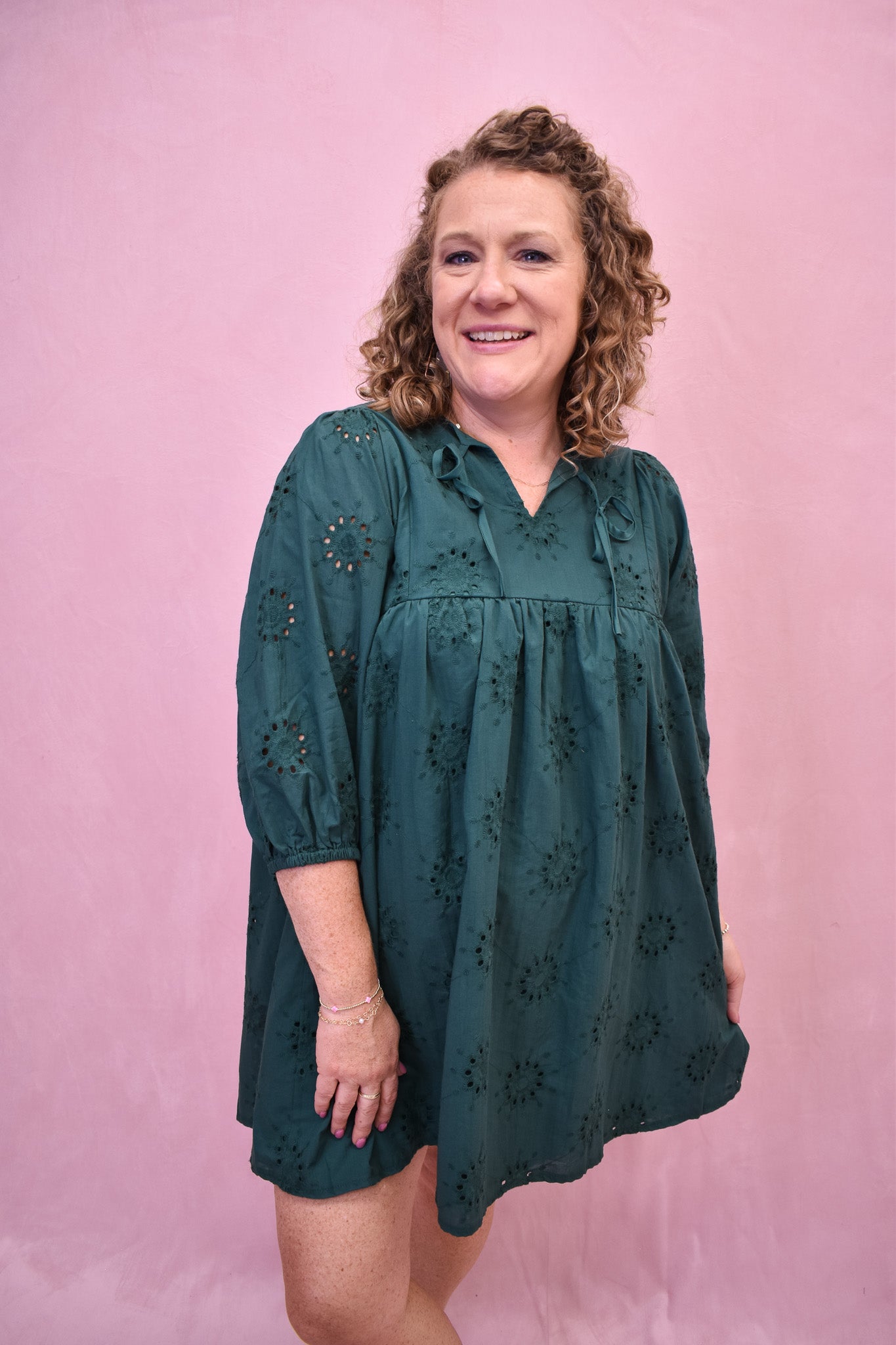 Woman wearing a green dress against a pink background
