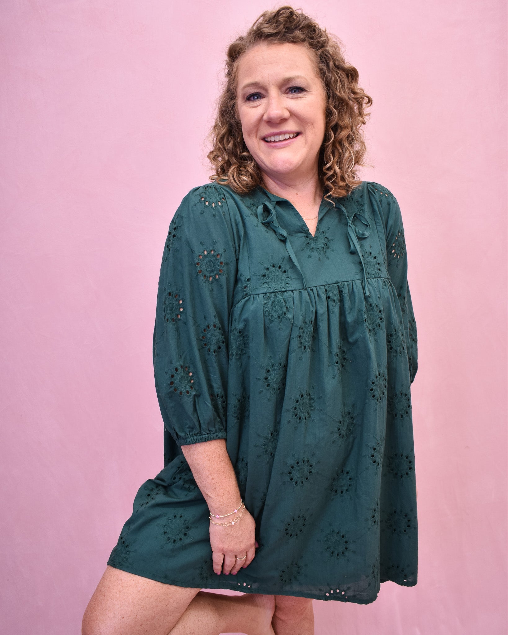Woman wearing a green dress against a pink background