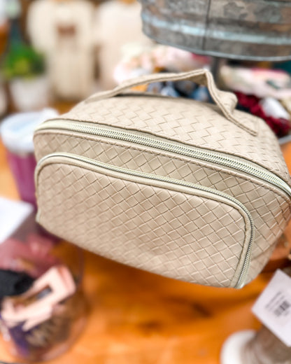 Beige woven cosmetic bag on a wooden surface with blurred background
