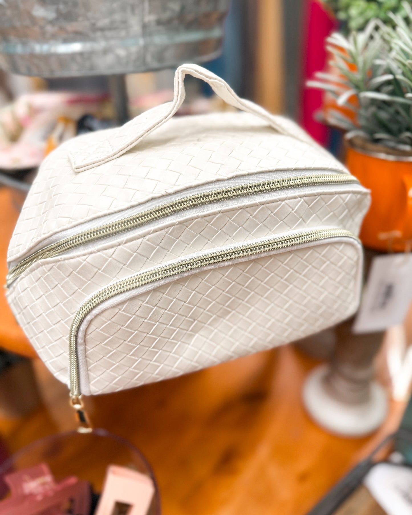 White textured cosmetic bag with gold zipper on a blurred background