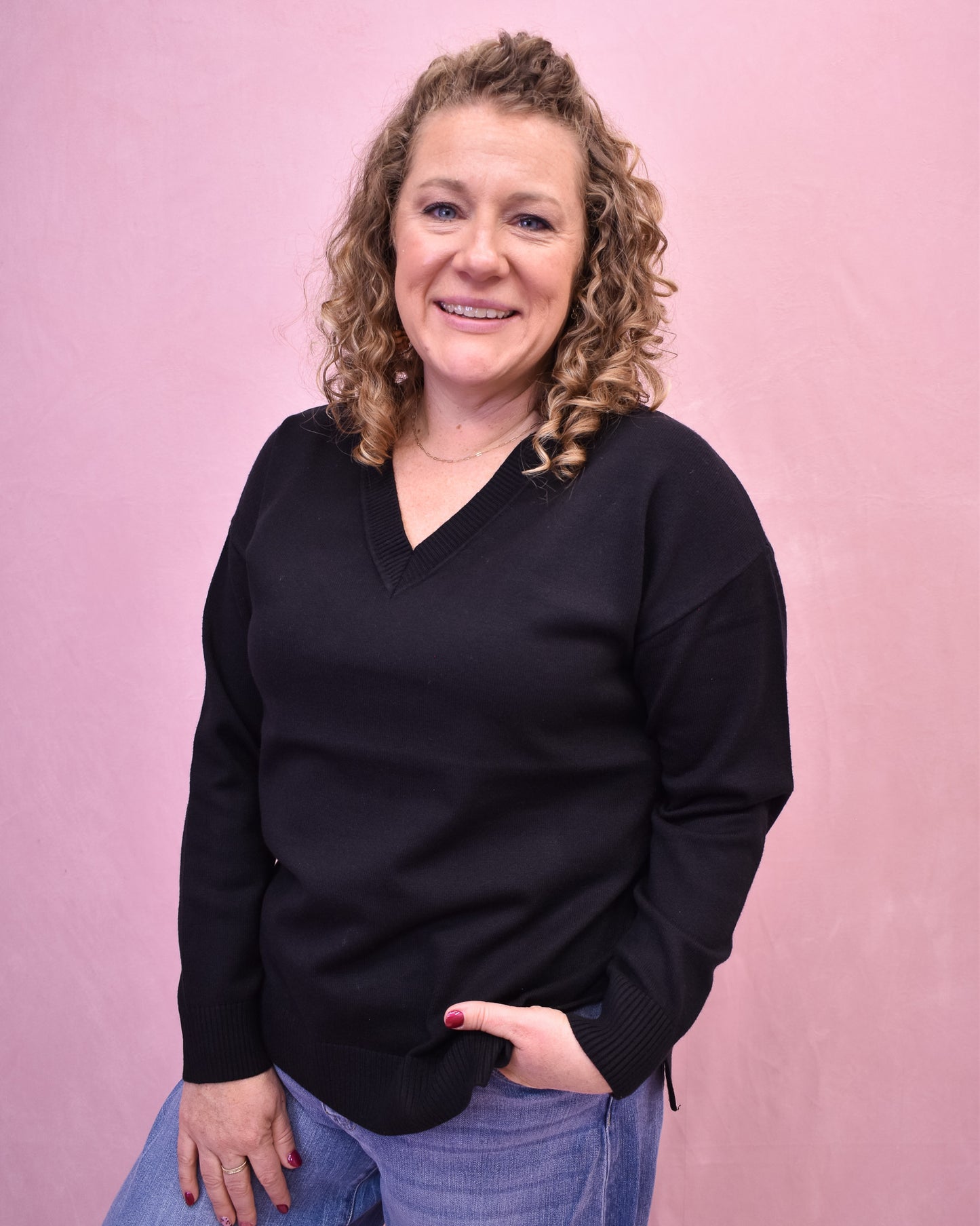 Woman wearing a black sweater against a pink background
