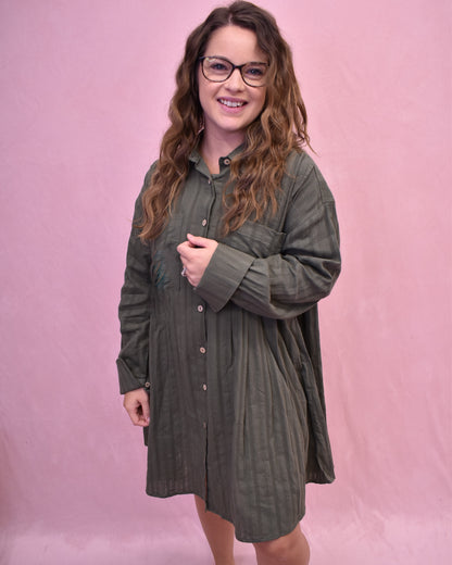 Woman wearing a green dress with long sleeves against a pink background