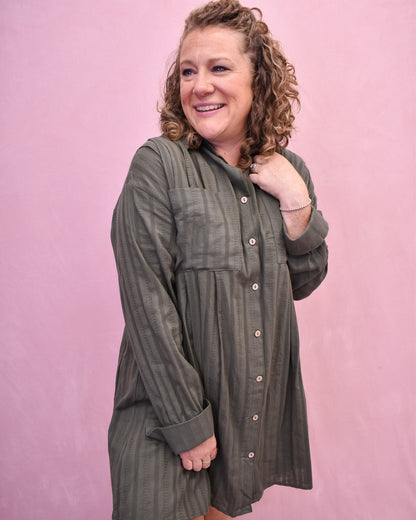 Woman wearing a green plaid dress against a pink background