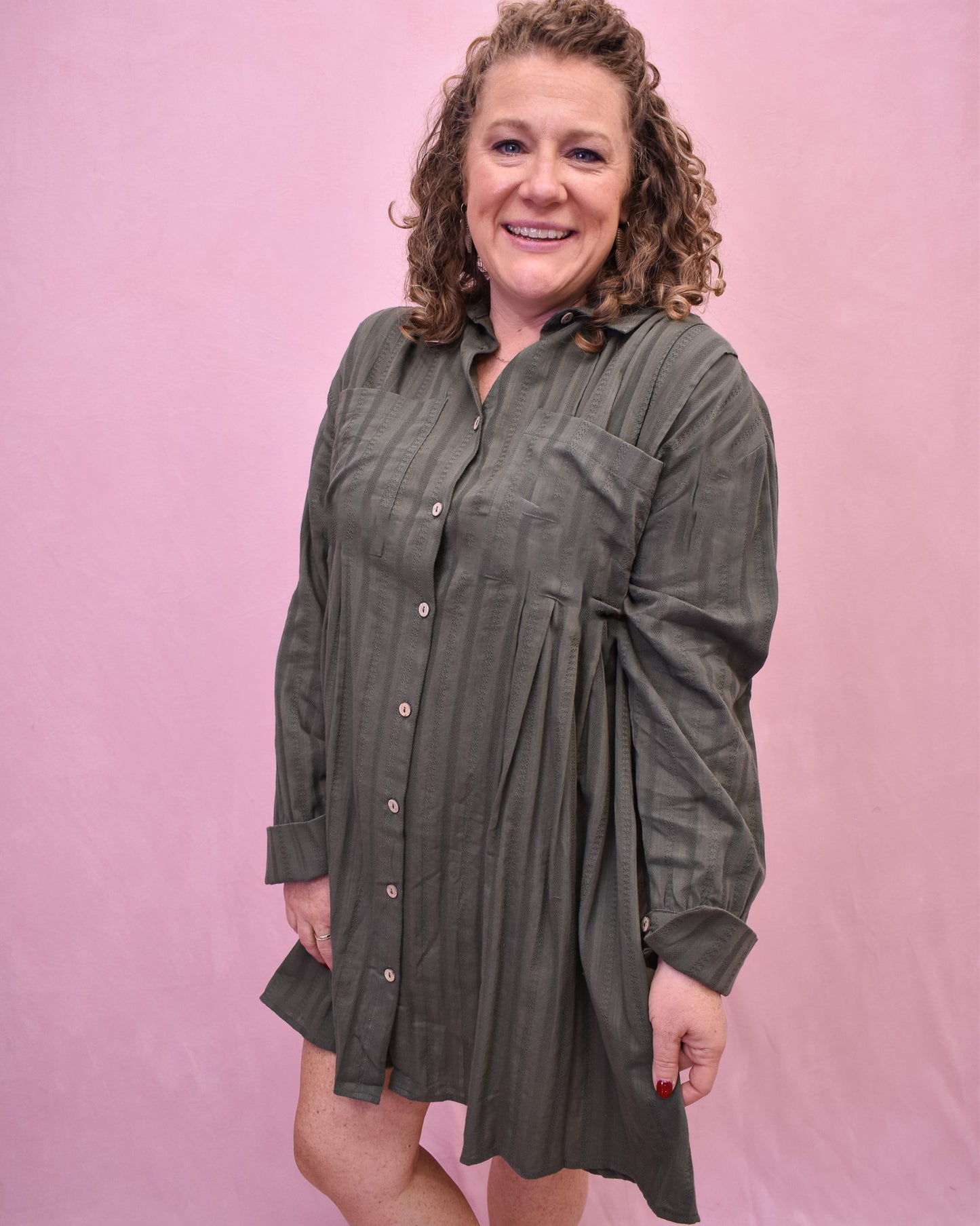 Woman wearing a green dress against a pink background