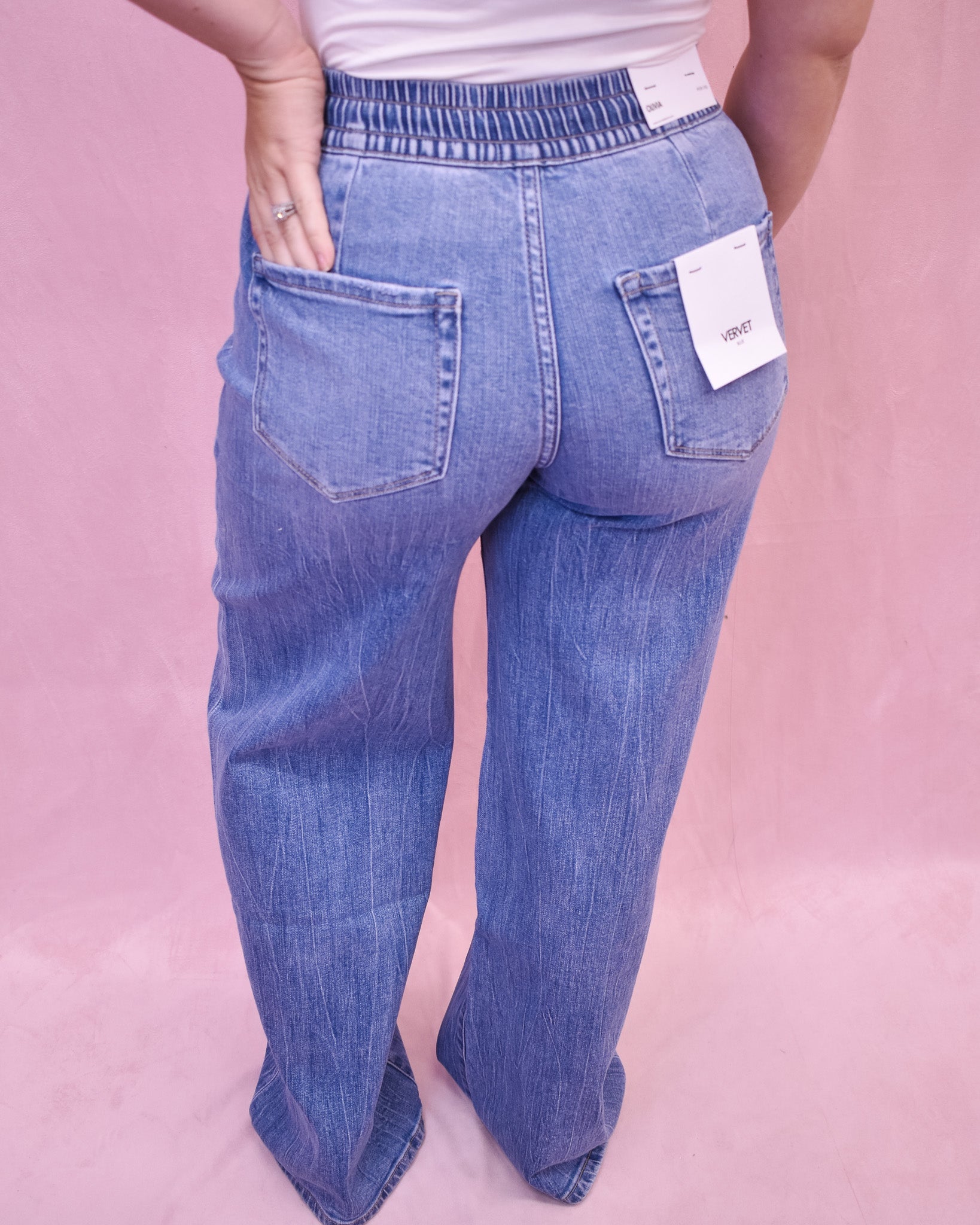 Blue jeans with a tag on a pink background