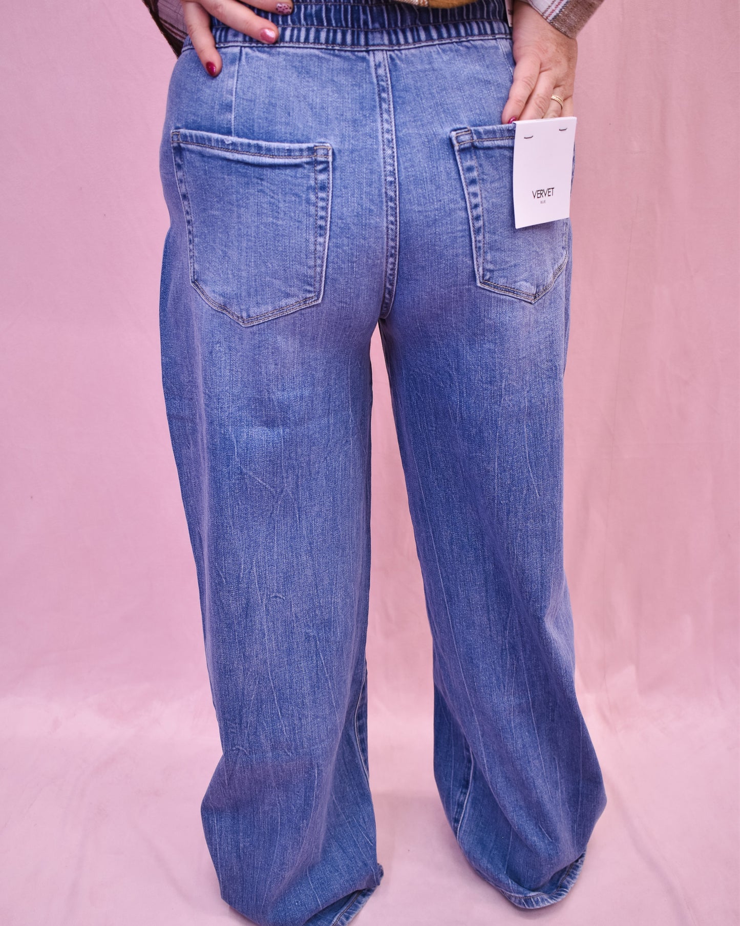 Blue jeans with a tag on a pink background