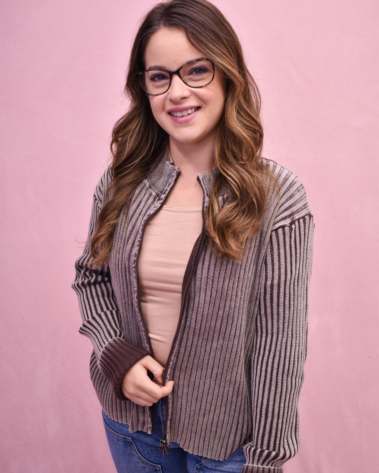 Woman wearing a striped shirt over a pink top on a pink background