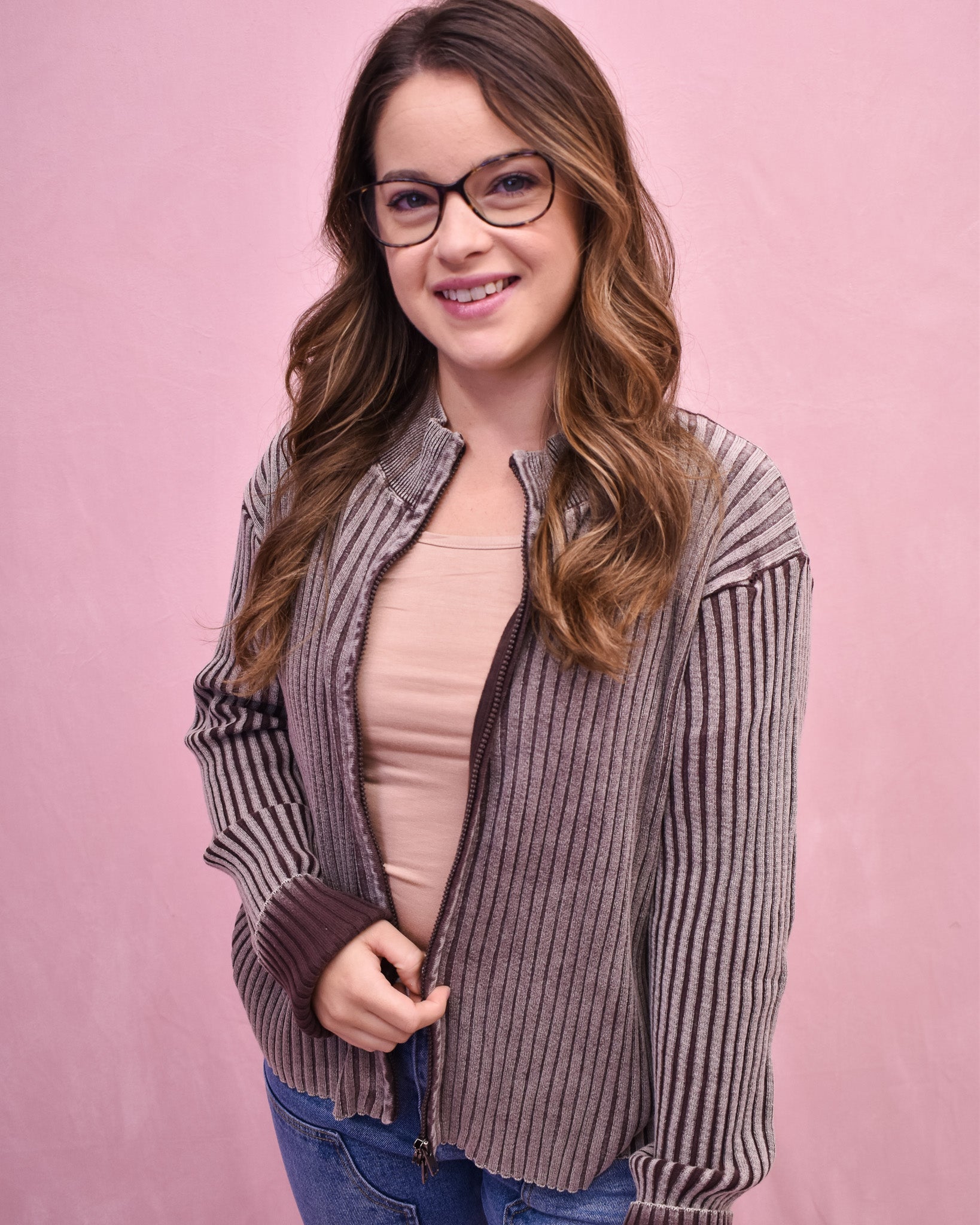 Woman wearing a striped shirt over a pink top on a pink background