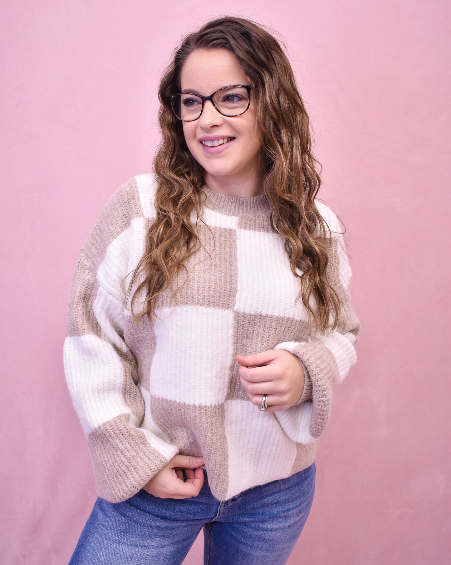 Woman wearing a checkered sweater against a pink background