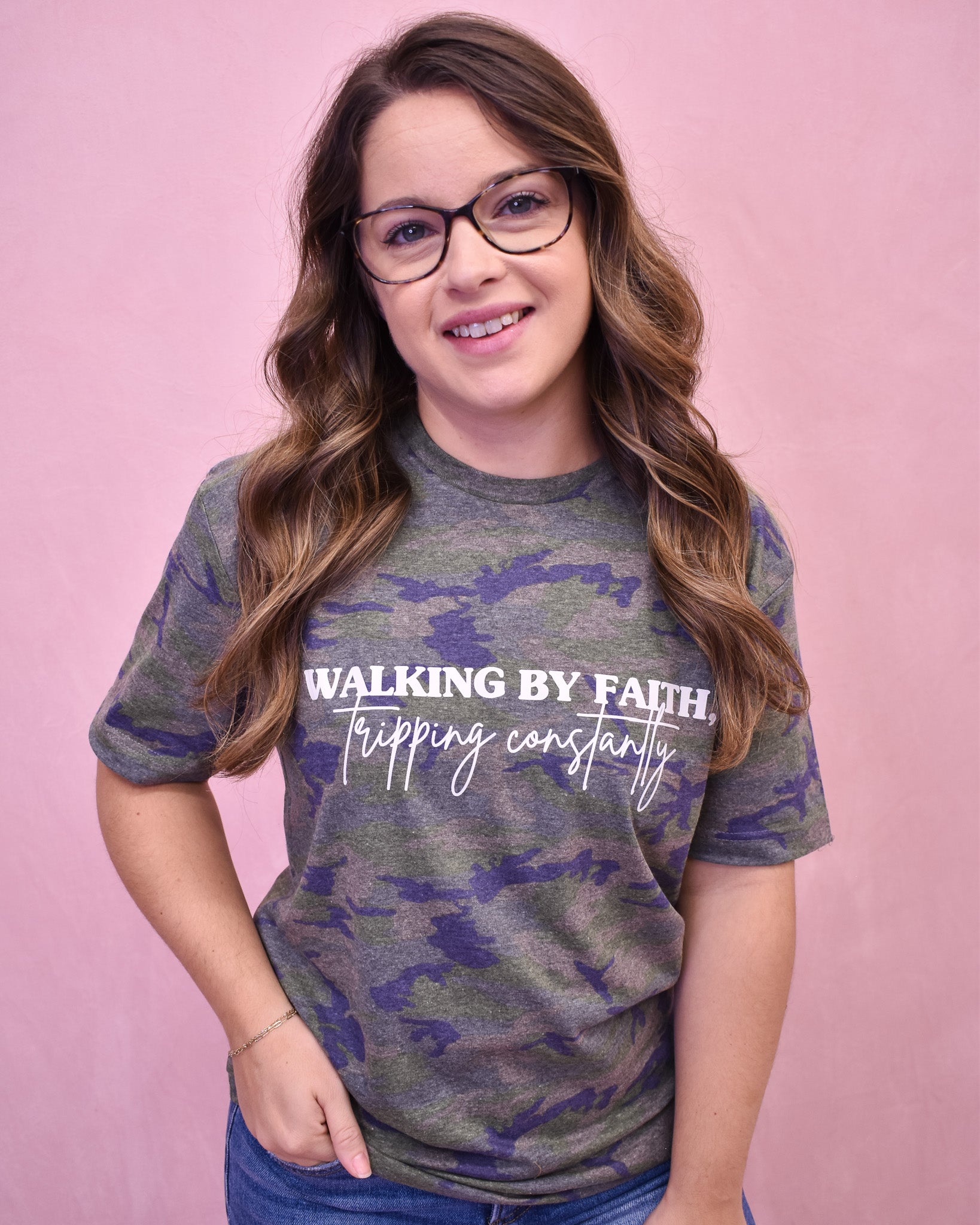 Person wearing a camouflage t-shirt with text on a pink background