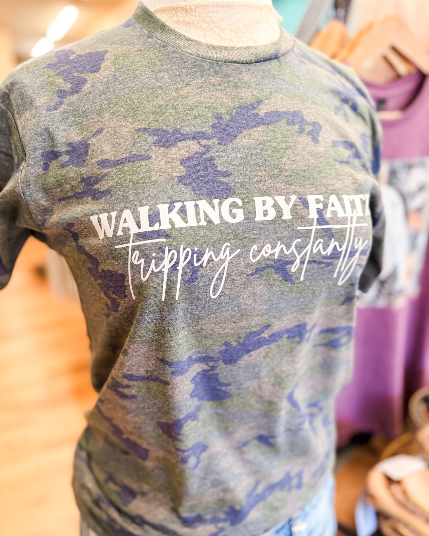 Camouflage t-shirt with text on a mannequin in a store setting