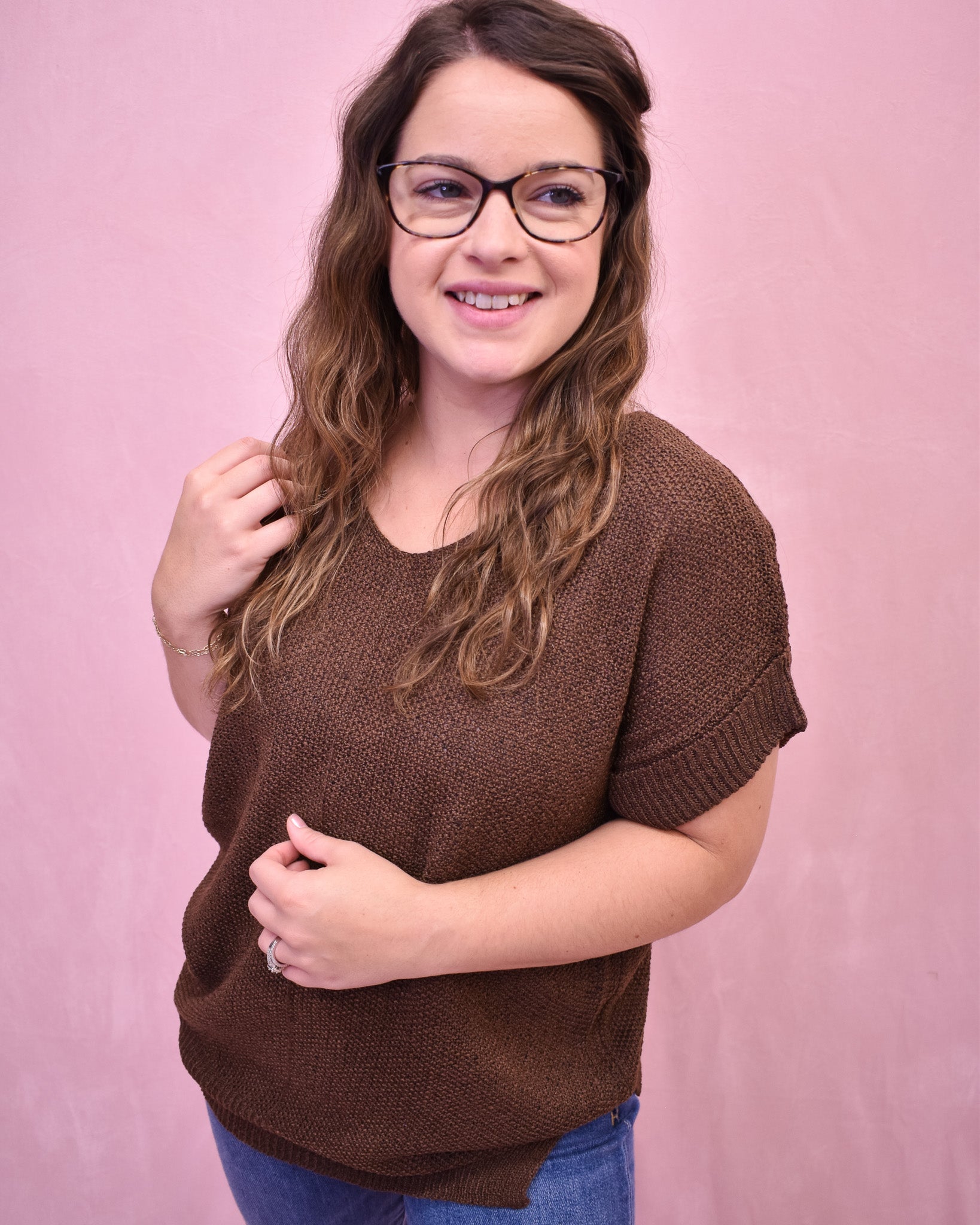 Woman wearing a brown sweater against a pink background