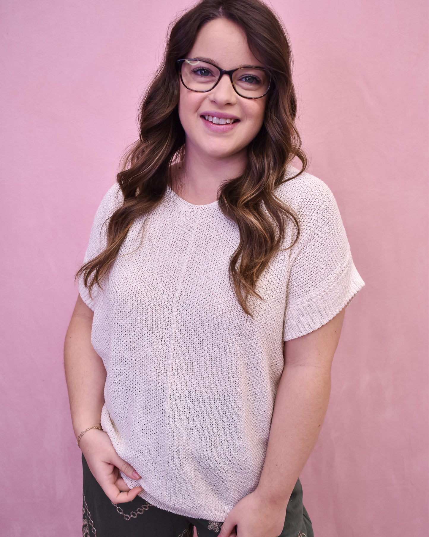 Woman wearing a light pink knitted sweater against a pink background