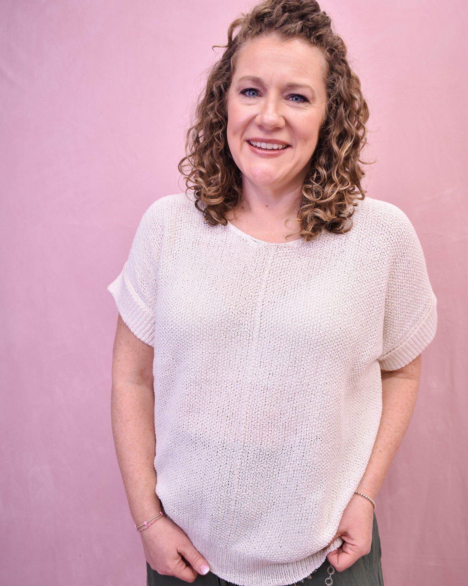 Woman wearing a light pink knitted sweater against a pink background