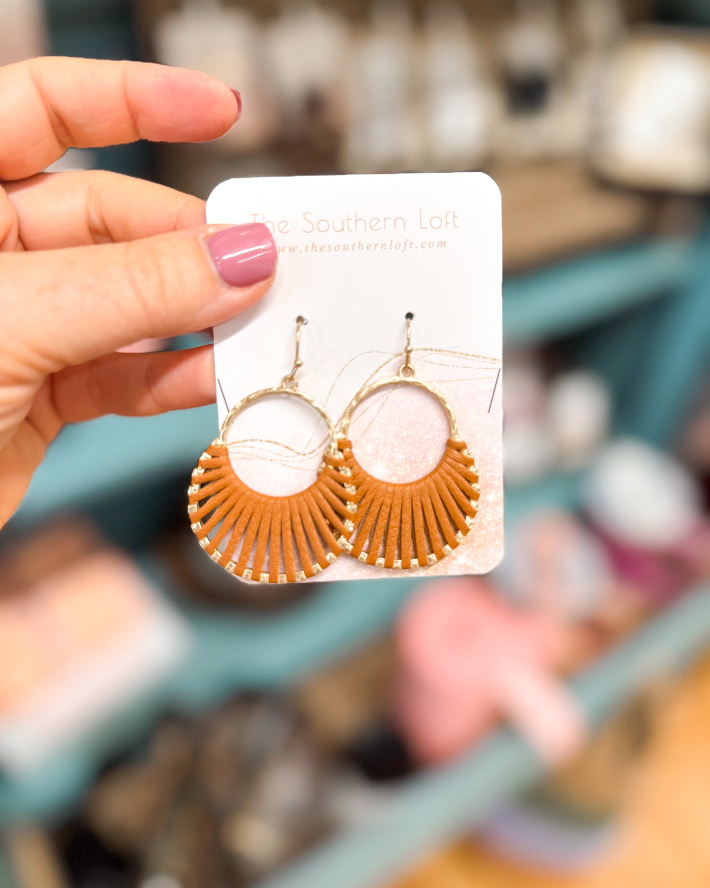 Hand holding a card with round earrings on a blurred store background